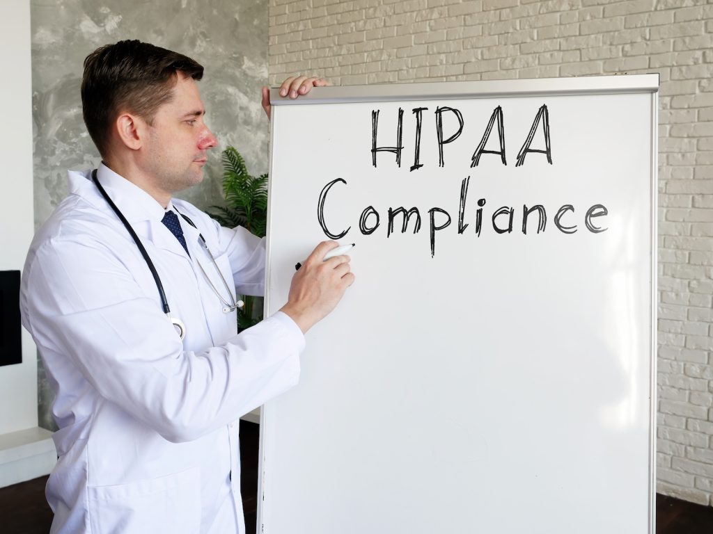 doctor writing the phrase hipaa compliance on a white board